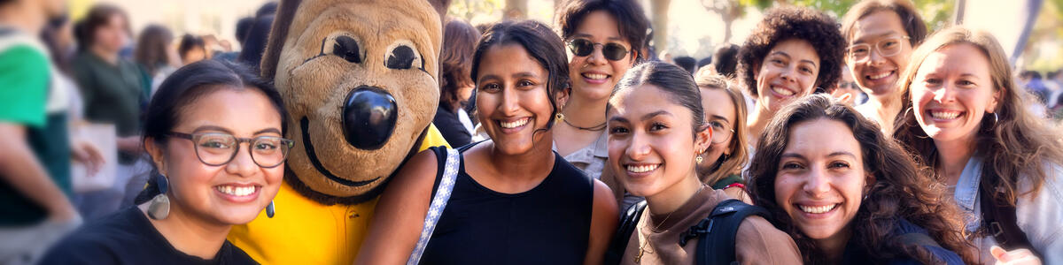 Students smiling and posing for a picture with the Oski bear mascot