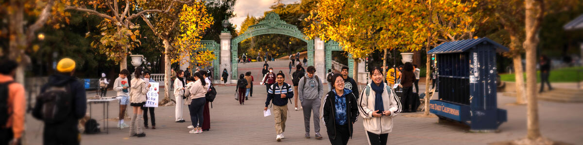 Sather Gate in the fall time with students walking about and golden leaves on the trees